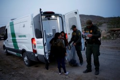 Migrants from Central America who were detained hand over their belongings to U.S. Border Patrol agents after crossing into the United States from Mexico
