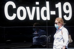 A woman wearing a mask passes by a coronavirus disease mobile testing van, as cases of the infectious Delta variant of COVID-19 continue to rise, in Washington Square Park