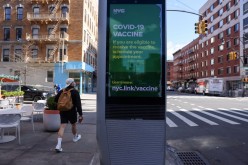 A pedestrian walks past an ad encouraging those eligible to sign up for COVID-19 vaccine appointments in the Manhattan borough of New York City, New York, U.S.