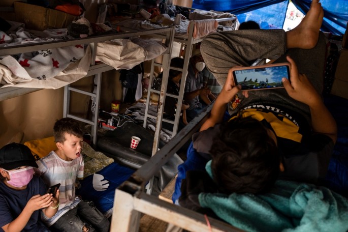 Asylum-seeking migrants from Central America, who were sent back to Mexico under Title 42 after crossing the border into the U.S. from Mexico, rest on beds in a public square where hundreds of migrants live in tents,