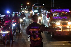A policeman inspects vehicles at a checkpoint placed to prevent the spread of the coronavirus disease (COVID-19), in Quezon City, Metro Manila, Philippines