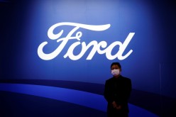A man stands near the Ford logo during a media day for the Auto Shanghai show in Shanghai, China