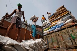 A labourer carries a sack filled with sugar to load it onto a supply truck at a wholesale market in Kolkata, India,
