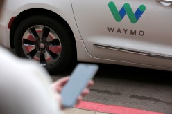 A Waymo employee hails a ride on their phone during a demonstration in Chandler, Arizona,