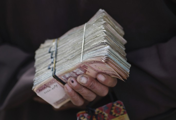 A money changer holds a stack of Afghan currency on a street in central Kabul