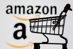 Small toy shopping cart is seen in front of displayed Amazon logo in this illustration,