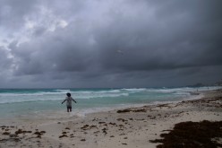 A tourist stands on a beach as Hurricane Grace approaches, in Cancun, Mexico,