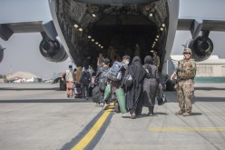 Families begin to board a U.S. Air Force C-17 Globemaster III transport plane during an evacuation at Hamid Karzai International Airport, Afghanistan