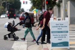 People walk past a sign for a coronavirus disease (COVID-19) vaccination clinic in Los Angeles, California, U.S.