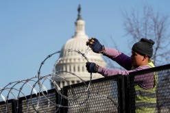 A worker removes razor wire from the top of security fencing as part of a reduction in heightened security measures taken after the January 6th attack on the U.S. Capitol in Washington, U.S.,