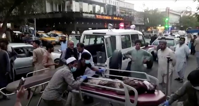 A screen grab shows people carrying an injured person to a hospital after an attack at Kabul airport, in Kabul, Afghanistan