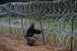 A Polish soldier builds a fence on the border between Poland and Belarus near the village of Nomiki, Poland