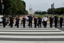 Law enforcement officers from Washington's Metropolitan Police Department, the U.S. Capitol Police, the Pentagon Force Protection Agency and other police departments salute as a ceremonial procession in honor of a police officer wounded