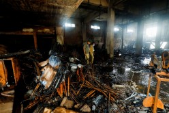 Members of the scout emergency response team, survey amid the burned wreckage, after a fire broke out at a multi-story chemical factory, in Karachi, Pakistan