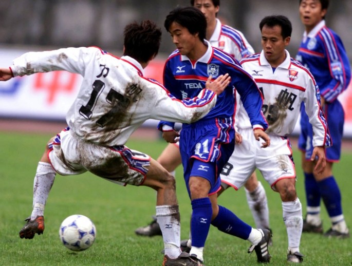 Chongqing Lifan's Li Guoxu (L) spars with Tianjin Taida's Han Yanming. The 2013 League One champs face possible dismissal after China's governing body rejected their takeover by Huaxia Guorui.