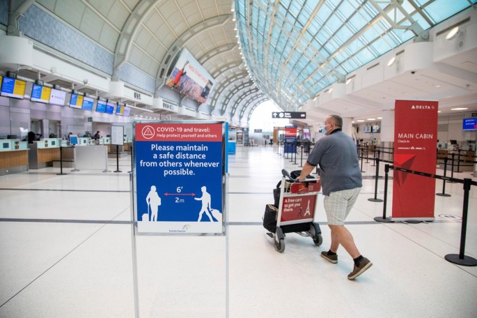 A man pushes a baggage cart wearing a mandatory face mask as a "Healthy Airport" initiative is launched for travel, taking into account social distancing protocols