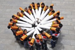 Students pose for pictures with ''big cigarette models'' for a campaign.