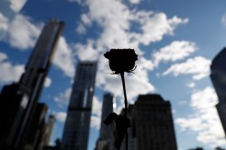 A flower seen in silhouette stands on the south reflecting pool at the 9/11 Memorial site in the lower section of Manhattan, New York City, U.S.,