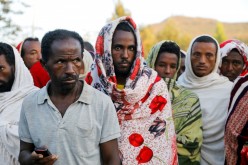 Men stand in line to receive food donations, at the Tsehaye primary school, which was turned into a temporary shelter for people displaced by conflict, in the town of Shire