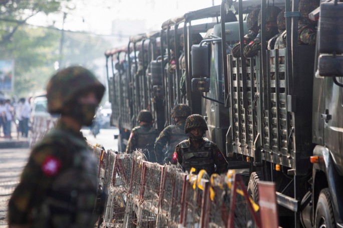 Soldiers stand next to military vehicles as people gather to protest against the military coup, in Yangon, Myanmar,