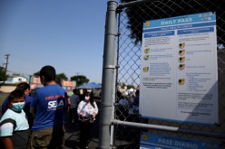 People wait in line at a school for coronavirus disease (COVID-19) testing and vaccines in South Gate, Los Angeles, California, U.S.