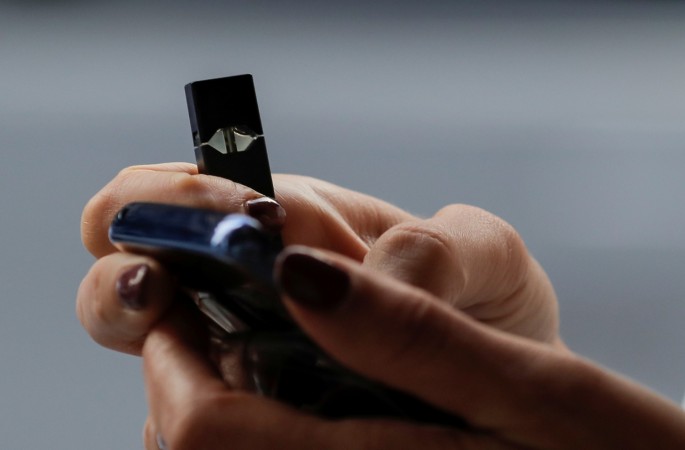 A woman holds a Juul e-cigarette while walking in New York, U.S.,