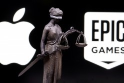 3D printed Lady Justice figure is seen in front of displayed Apple and Epic Games logos in this illustration photo taken