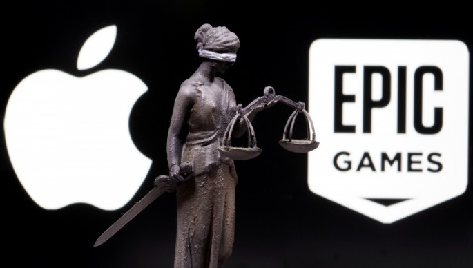 3D printed Lady Justice figure is seen in front of displayed Apple and Epic Games logos in this illustration photo taken
