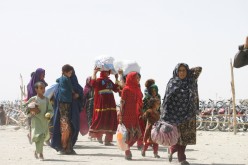 People from Afghanistan walk with their belongings as they cross into Pakistan at the 'Friendship Gate' crossing point, in the Pakistan-Afghanistan border town of Chaman, Pakistan,