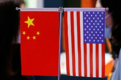 Staff members chat behind Chinese and U.S. flags displayed at the 2021 China International Fair for Trade in Services (CIFTIS) in Beijing, China