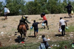 A U.S. law enforcement officer on horseback chases migrants returning to the United States after buying food in Mexico, as seen from Ciudad Acuna, Mexico 