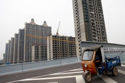A vehicle drives past unfinished residential buildings at Evergrande Oasis, a housing complex developed by Evergrande Group, in Luoyang, China