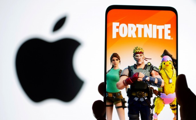 Fortnite game graphic is displayed on a smartphone in front of Apple logo in this illustration