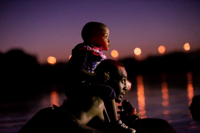 A migrant seeking refuge in the U.S. crosses the Rio Grande river with his son on shoulders, at the border towards Del Rio, Texas, U.S., as seen from Ciudad Acuna, Mexico