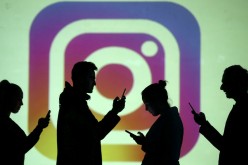  Silhouettes of mobile users are seen next to a screen projection of Instagram logo in this picture illustration taken
