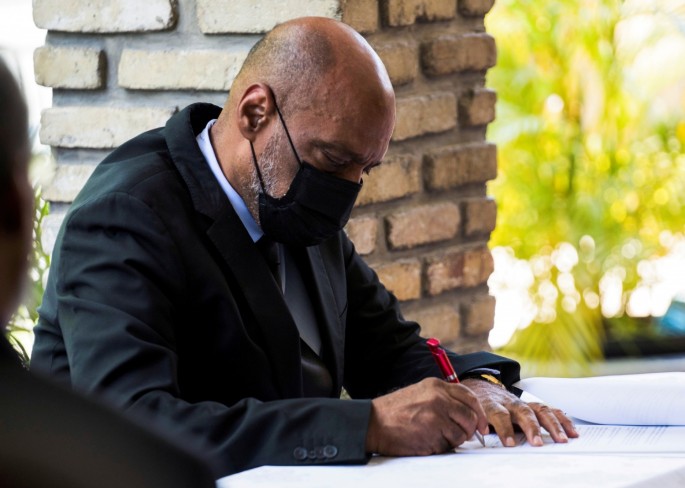 Prime Minister Ariel Henry signs a document at an office during the signing ceremony of the "Political Agreement for a peaceful and effective governance of the interim period" with the opposition in Port-au-Prince, Haiti.