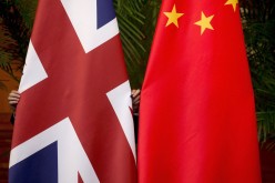 A worker adjusts British and China (R) national flags on display for a signing ceremony at the seventh UK-China Economic and Financial Dialogue 