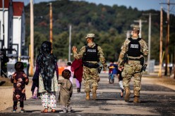 U.S. Military Police walk past Afghan refugees at the Village at Fort McCoy U.S. Army base, in Wisconsin, U.S.
