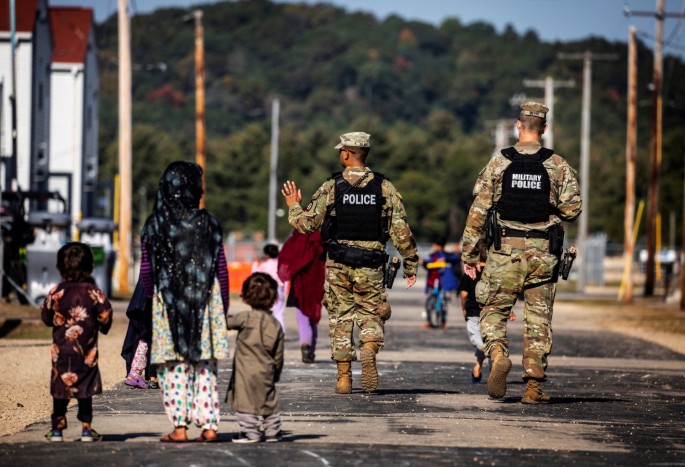 U.S. Military Police walk past Afghan refugees at the Village at Fort McCoy U.S. Army base, in Wisconsin, U.S.