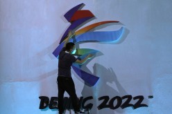 A man adjusts an emblem of the Beijing 2022 Winter Olympic Games before a ceremony unveiling the slogan, in Beijing, China