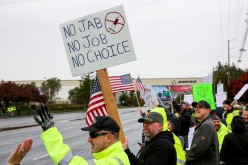 Boeing employees and others line the street with signs and American flags as they protest the company's coronavirus disease (COVID-19) vaccine mandate, outside the Boeing facility in Everett, Washington,