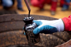 A worker collects a crude oil sample at an oil well operated by Venezuela's state oil company PDVSA in Morichal, Venezuela