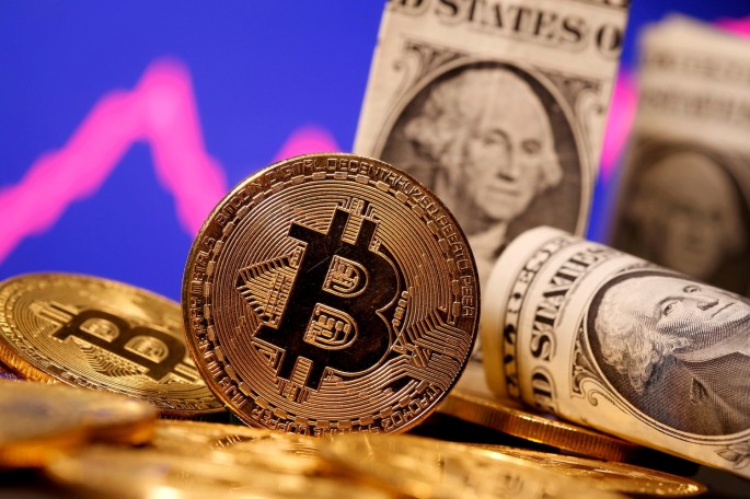 A representation of virtual currency Bitcoin and U.S. One Dollar banknotes are seen in front of a stock graph in this illustration taken