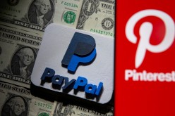 A Pinterest logo is seen on a smartphone placed over U.S. dollar banknotes and a 3D printed PayPal logo in this illustration taken