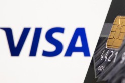 Credit card is seen in front of displayed Visa logo in this illustration taken,