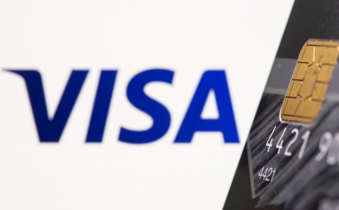 Credit card is seen in front of displayed Visa logo in this illustration taken,