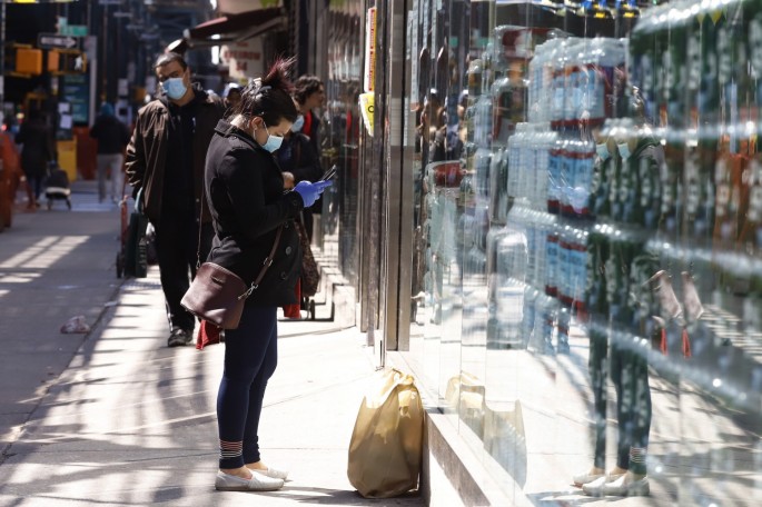 A woman texts on her mobile phone as she waits for a friend outside a supermarket on Roosevelt Avenue during the outbreak of the coronavirus disease (COVID-19) in the Queens borough of New York City, New York, U.S