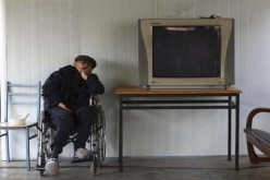 A man sleeps in a wheelchair next to a television set at a nursing home.