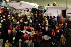 Rescuers carry one body in a bag away after a TransAsia Airways plane crash