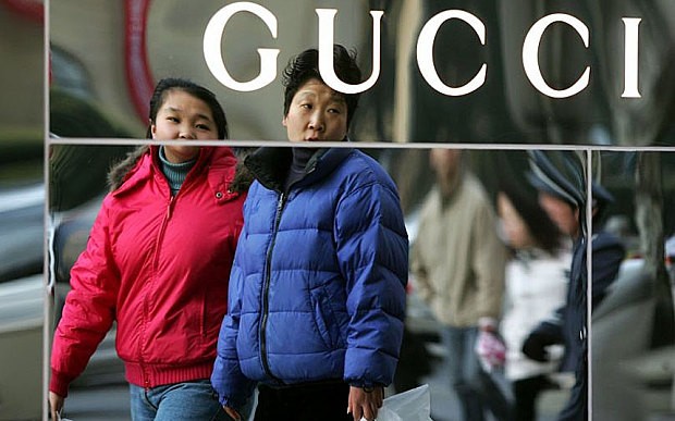 Chinese tourists walking outside a flagship store of Italy's Gucci luxury brand.